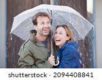 Small photo of Happy couple under umbrella in downpour