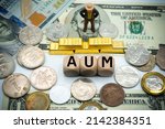 Small photo of Assets under management (AUM) is the total market value of the investments that a person or entity manages on behalf of clients.The word is written on money and gold background