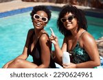 Small photo of Two Black friends apply sunscreen, acting silly having fun, laughing at pool