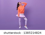 Full length view of trendy korean girl with skateboard. Studio shot of gorgeous asian woman holding longboard on purple background.