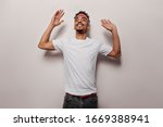 Joyful guy in white T-shirt and black jeans is dancing. Portrait of charming man in tee and pants smiling on isolated background