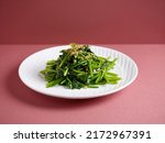 Stir-Fried Spinach with Garlic with chopsticks served in a dish isolated on mat side view on grey background