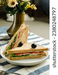 Small photo of Mortadella and Multigrain Bread sandwich topping with black olive served in plate isolated on napkin side view of breakfast food