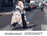 Small photo of Milan, Italy - February 26, 2022: Woman in stylish poncho walking on the street in daytime.