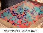Small photo of Oil-based inks in a tank of water being prepared for marbling. Paper marbling is a method of aqueous surface design.