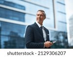 Small photo of Hard work, determination, persistence creates a boss. Shot of a handsome mature businessman in corporate attire using a cellphone outside outside during the day.