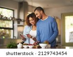 Small photo of Using a step by step online recipe. Shot of a happy young couple using a digital tablet while preparing a healthy meal together at home.