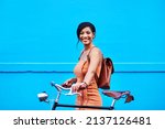 Small photo of En route to happiness. Portrait of an attractive young woman traveling with her bicycle against a blue background.