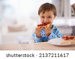 Nothing beats a good breakfast. A cute little boy eating toast with jam.
