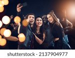 Small photo of One more just because we can. Cropped shot of a diverse group of young friends taking a selfie together at a party at night.