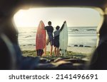 Small photo of Lets go catch some waves, little bro. Rearview shot of two brothers holding their surfboards while standing on the beach.