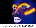 Neon celebration. A young woman with with neon paint on her face posing.