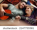 Small photo of Did like that little ditty. Shot of a young man playing guitar while lying on the floor with his girlfriend.