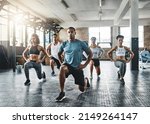 Small photo of Every step taken towards fitness pays off. Shot of a group of young people doing lunges together during their workout in a gym.