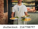Small photo of I got what you ordered right here sir. Shot of an unrecognizable waiter holding three plates of food that hes going to serve to customers inside of a restaurant during the day.