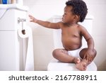 Small photo of Potty training 101 Always make sure you have enough toilet paper. Shot of a baby boy sitting on the toilet and reaching for the toilet paper.