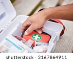 Everything he needs to treat your injuries. High angle shot of an unrecognizable male paramedic looking in his first aid kit while standing outside.
