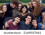 Small photo of Life is brighter with friends. Portrait of a group of young students standing arms around each other outside in a park during the day.