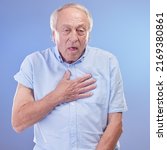 Small photo of Shortness of breath could shorten your life, get it checked. Studio shot of a senior man experiencing chest discomfort against a blue background.