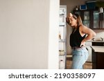 Plus size, chubby and hungry woman looking in a fridge, thinking of food or searching for meal while on a diet. Stressed, anxious and frustrated lady struggling with weight loss management