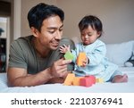 Small photo of Baby, down syndrome and learning on a bed with child and father playing with educational blocks in a bedroom. Family, disability and kids bonding with asian parent, relax with creative activity