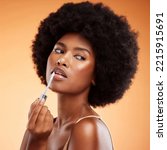 Small photo of Black woman, afro and natural beauty lip gloss treatment for a healthy, shiny and transparent tint. Cosmetics, apply and beautiful face of African model holding makeup tool at orange background.