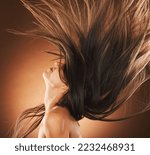 Small photo of Beauty, hair and freedom with a model woman in studio on a brown background for strong haircare. Wellness, luxury and salon with an attractive young female hair flick to promote a keratin product