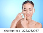 Small photo of Woman, skincare and squeeze pimple on face with blue studio background. Skin care, morning facial and young model with flaws, blemish and imperfection pop acne or blackhead with fingers and hands
