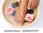 Small photo of Skincare, flowers and woman with feet in water bowl for cleaning or hygiene. Floral therapy, spa treatment and female model soak foot washing with pink roses and stones for detox, beauty or pedicure.