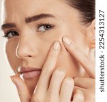 Small photo of Portrait, hands and pimple with a woman checking or examining her skin for acne problems in studio. Face, fingers and breakout with an attractive young female indoor to squeeze or pop a blackhead