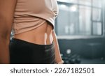 Small photo of Fitness, stomach and woman in a gym for exercise, health or wellness for weightloss training. Sports, tummy tuck and closeup of a slim female athlete or model abs after a workout in a sport center.