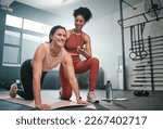 Personal trainer, exercise and stopwatch with a black woman coaching a client in a gym during her workout. Health, fitness or training and a female athlete ready to plank with a coach recording time