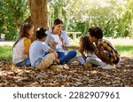 Small photo of Books, reading or teacher with children in a park storytelling for learning development or growth. Smile, tree or happy educator with stories for education at a kids kindergarten school in nature