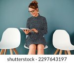 Small photo of Getting rid of interview jitters Theres an app for that. Studio shot of an attractive young businesswoman using a digital tablet while sitting in line against a grey background.