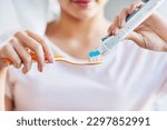 Small photo of Just a little goes a long way. Closeup shot of a young woman squeezing toothpaste onto her toothbrush in the bathroom at home.