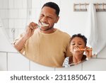 Brushing teeth, father and child in a home bathroom for dental health and wellness with smile. Face of a man and african boy kid learning to clean mouth with a toothbrush and mirror for oral hygiene