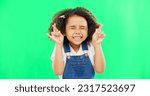 Small photo of Fingers crossed, wish and praying with girl in studio for good luck, hope and optimism. Excited, emoji and closed eyes with child isolated on green background for miracle, positive and youth