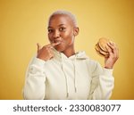 Small photo of Burger, eating and portrait of woman or student on studio yellow background for restaurant promotion or deal. Hungry and happy, african person or customer experience with fast food or hamburger taste
