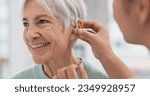 Small photo of Old woman, doctor hands and patient with hearing aid, help and support with healthcare in clinic. Person with disability, deaf and people, trust and communication, health insurance and medical