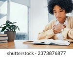 Small photo of Bible, prayer and woman studying religion at desk in home, Christian faith and knowledge of God for hope. Reading, praise and girl at table with holy book, learning gospel for inspiration or theology