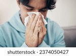 Small photo of Man, sick and couch with tissue, sickness and virus for infection, sinus and cold symptoms. Sneeze, blowing nose and allergy in living room sofa, hayfever and healthcare for disease, fever or alone