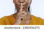 Small photo of Secret, finger to lips and black woman in studio for privacy, confidential information and face on white background. Mouth zoom, quiet and silence gesture with emoji, gossip or whisper with news