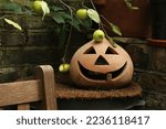 Small photo of Green apples growing overtop of a ceramic jack-o-lantern outside with a rustic brick background. Autumn wallpaper, concept for harvest, Halloween, fall, outdoors, cozy, holidays, end of summer