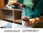 Woman pooring glass of red wine 