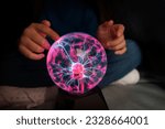 plasma ball. Hands holding plasma light ball. Plasma ball light ray science. Finger touching Plasma ball with smooth magenta blue flames. Electromagnetic Fields in a glass globe.