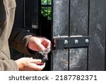 Small photo of Rural crime. A farmer holds a damaged padlock. A black padlock with a twisted shackle destroyed during a barn break in. Agricultural theft of tools and farm machinery. Rural crime in the countryside