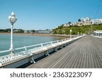 Small photo of Torquay, Devon, uk. 06-05-23. Torquay Princess pier looking towards the Princess theatre and Tor abbey sands. English riviera image of this Popular English town. Softly focused benches in foreground.