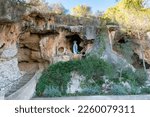 Small photo of Cave of Our Lady of Lourdes (Cova de Lourdes), outdoor rocky chapel with a wooden sculpture of the Virgin Mary and of Saint Bernadette. Santa Eugenia, Majorca, Spain.