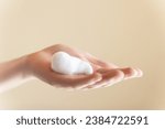 Small photo of Extreme close-up, hands on isolated background, young woman applying by hand foaming soap or foam for face wash, skin care, cleansing, hygiene, health care. Hand sanitizing foam