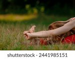 Small photo of Closeup of young woman flexing feet while stretching on yoga mat outdoor. Solo stretch: Young woman finds solace stretching legs in lush park.